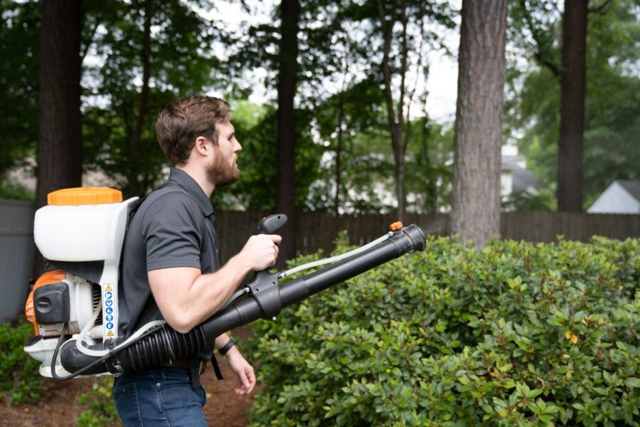 Nature's Turf emplyee spraying mosquito treatment on bushes