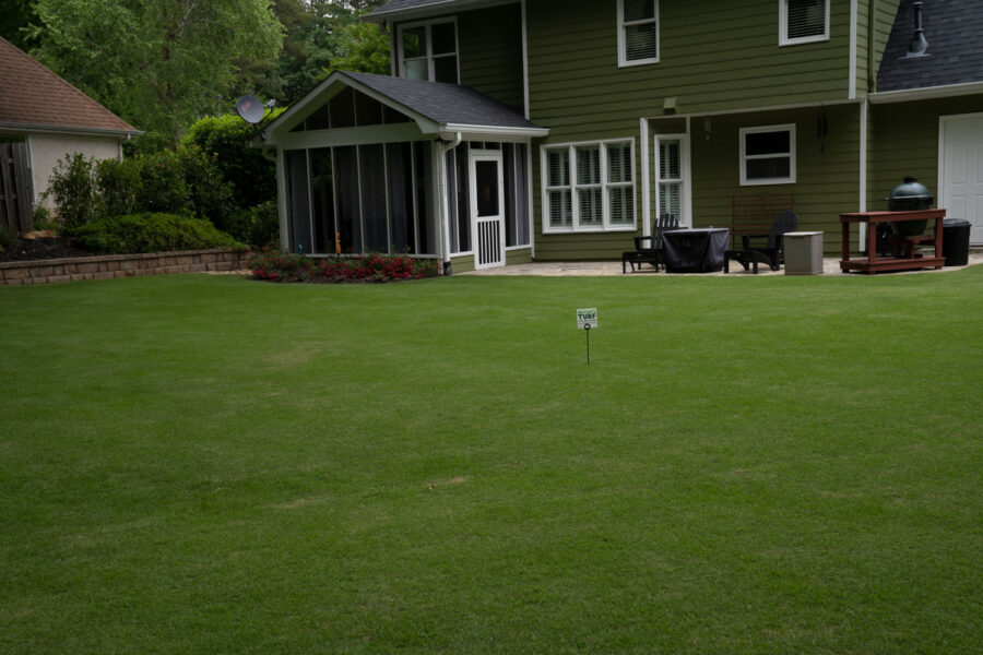 Lush, green backyard of a beautiful home with a Nature's Turf sign in the lawn