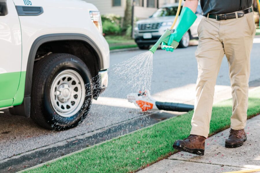 Nature's Turf employee spraying a lawn by a Nature's Turf truck