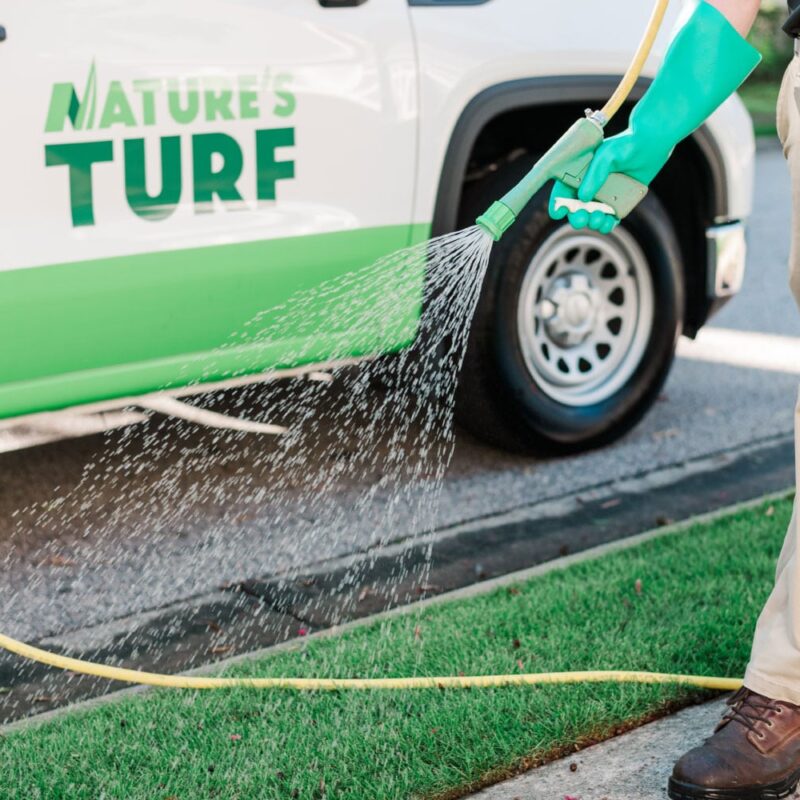 Nature's Turf employee spraying turf