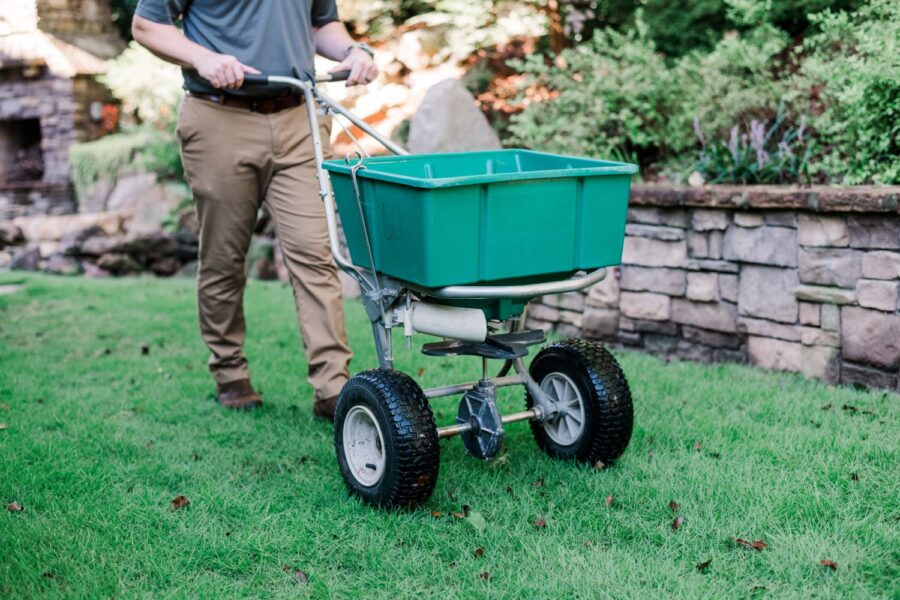Nature's Turf employee spreading product on a green lawn.