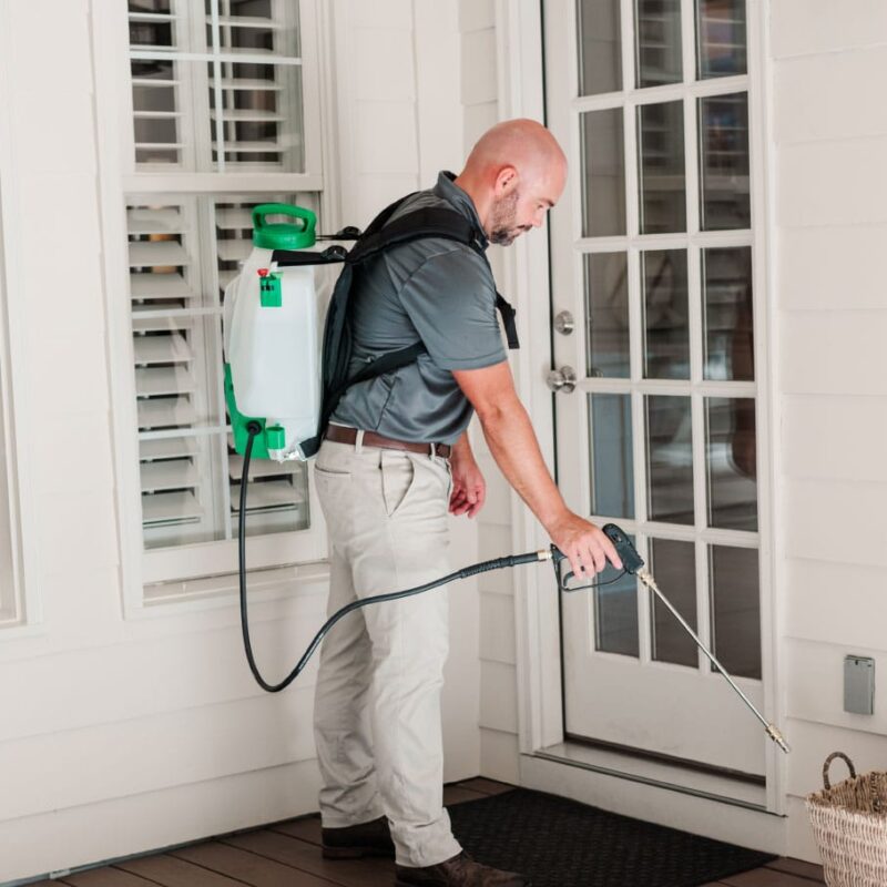 Nature's Turf employee spraying for ants around door of a home