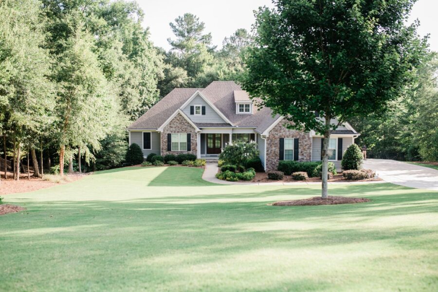 brick home with a lush, green lawn surrounded by mature trees